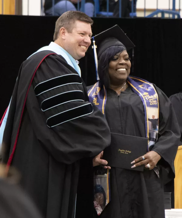 The college president shaking hands with a graduate