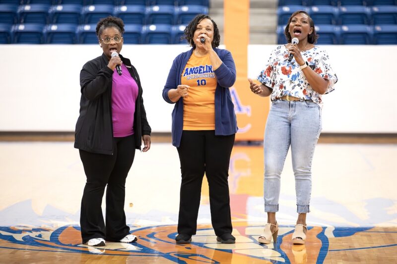 Three vocalists perform the national anthem at center court before an Angelina College home game against Tyler.