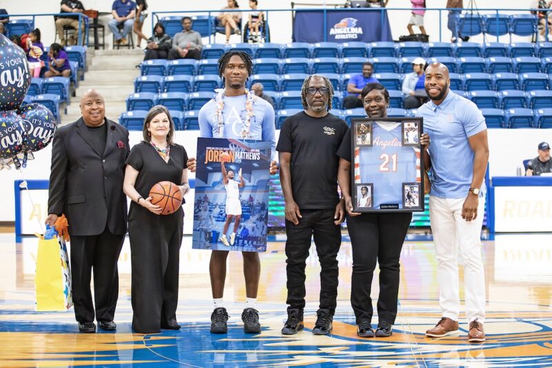 Jordan Mathews is recognized on Sophomore Day at center court, holding framed memorabilia and posing with family members.