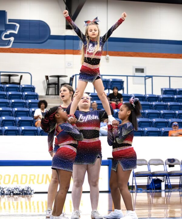Lufkin Parks and Recreation cheerleaders perform a stunt at center court during halftime of an Angelina College game.