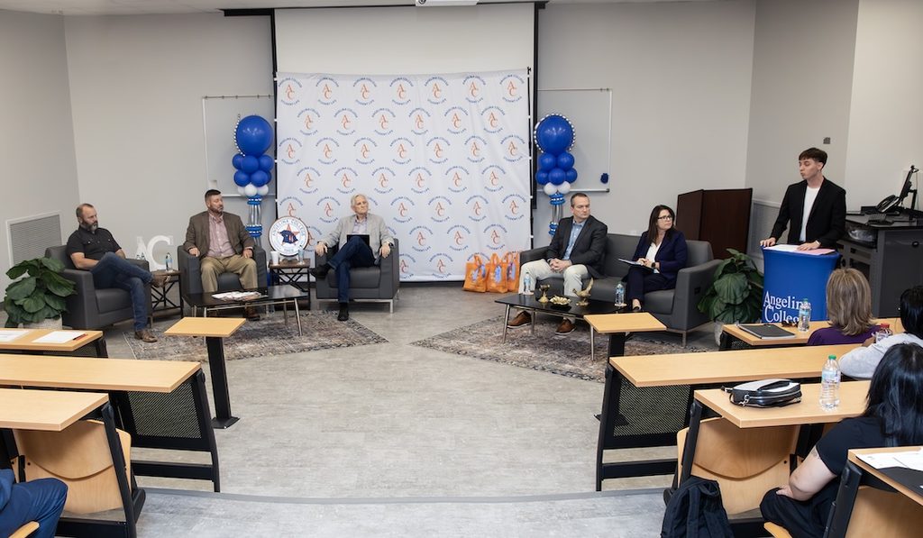 Five panelists seated on a stage during an Angelina College presentation as a speaker stands at a podium.